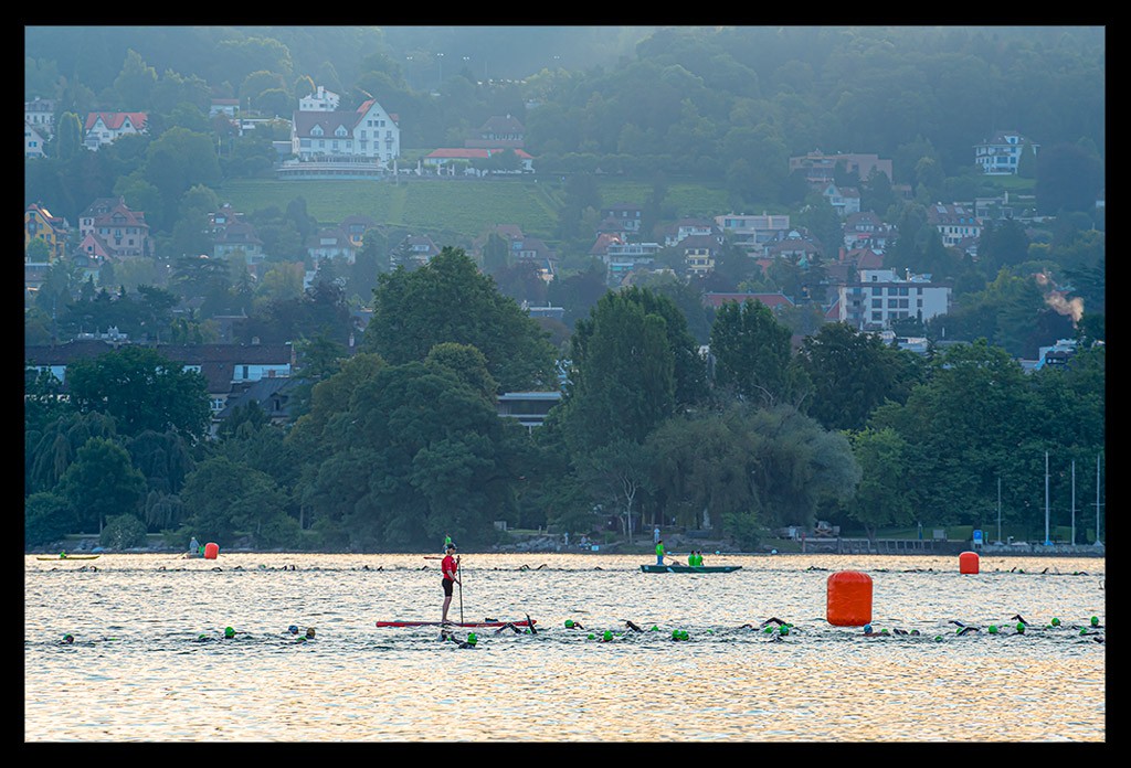 triathleten ironman schwimmen see zürich schweiz am morgen im wasser landschaft boje rettungswacht sup