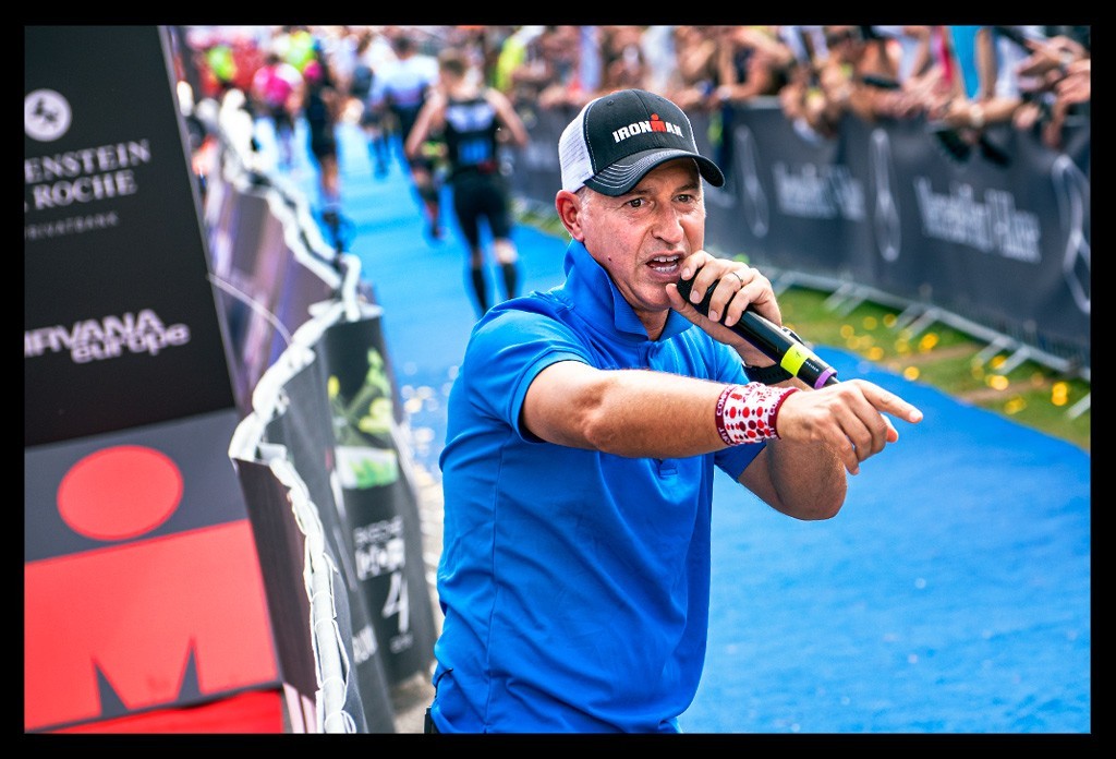 Paul Kaye Ironman announcer finish moderator mikrofon feuert athleten an ziel M-Logo hintergrund zuschauer crowd finishline jubel athleten laufen sommer zurich