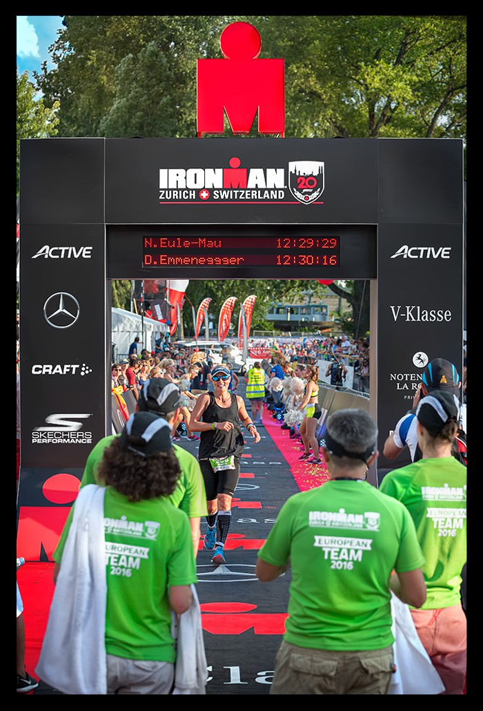 Ironman zurich zieleinlauf erste langdistanz triathletin nadin freude endzeit zusehen logo oben zielbogen sommerlich helfer mit medaillen