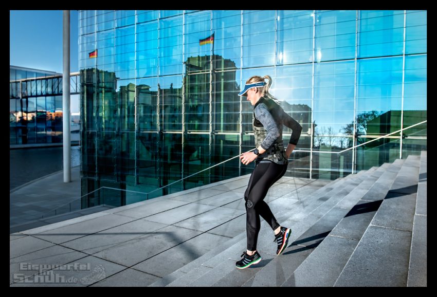 Athletin trainiert auf Treppe im Regierunsviertel in Berlin. Viel Armschwung. Im hintergrund Glasfasaden und spiegelung vom Reichstag. Der Garmin Forerunner 630 im Test.