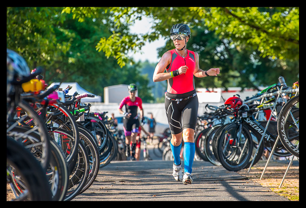 Ironman Frankfurt Wechselzone T1 Fahrräder aufgestellt Triathletin mit Helm Sprintet zu ihrem rad Langener Waldsee Radstrecke