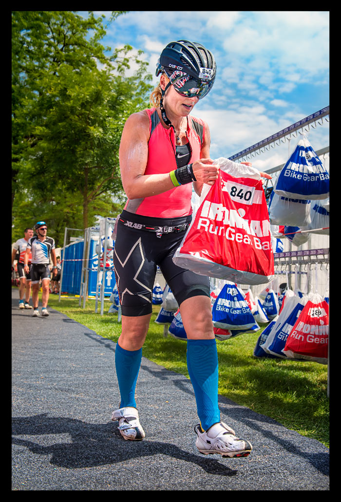 Ironman Frankfurt Wechselzone Triathletin greift zum Laufbeutel Tri-suit helm sonnenschein 