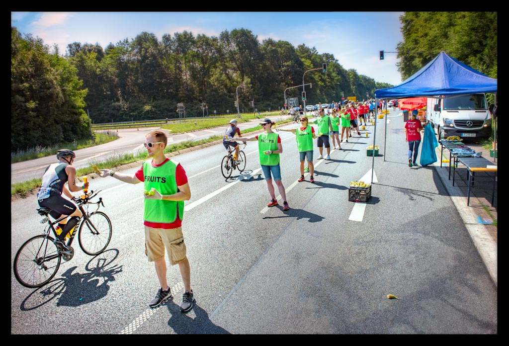 Ironman Frankfurt verpflegungsstation Wasserstation helfer stehen in reihe triathleten fahren vorbei bananen auf asphalt