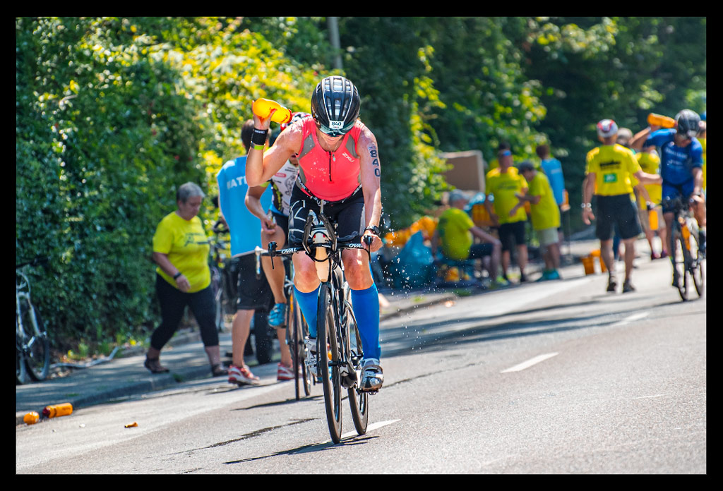 Ironman Frankfurt Wasserstation Sommer Hitze Radstrecke Athletin kippt Flasche über körper an verpflegungsstation helfer im hintergrund