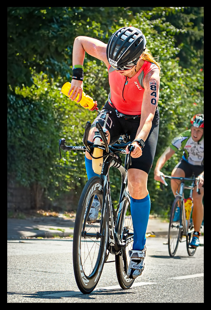 Ironman Frankfurt Radstrecke Triathletin blonde haare kühlt mit wasserflasche den körper sommerlich hitze