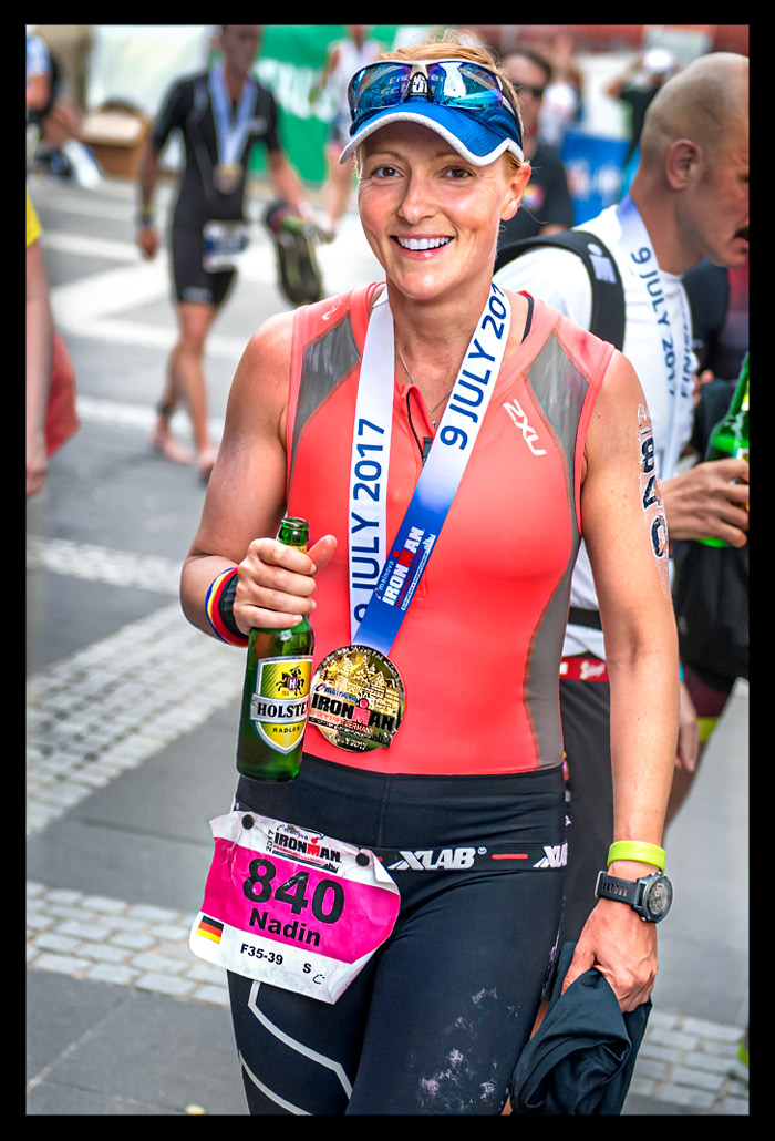 triathletin ziel finisher bier hand flasche lacht freude Medaille tri-suit offen