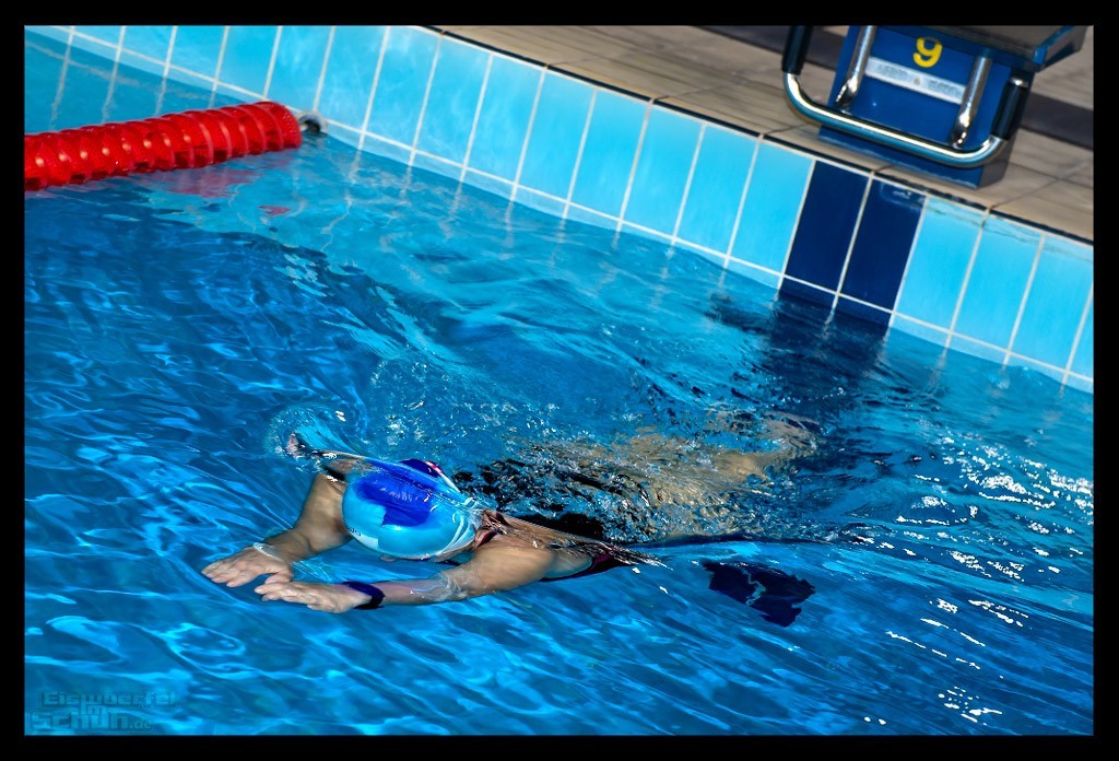 Triathletin in schwimmbecken halle tauchphase wende blaues wasser beckenrand licht spiegelt kraulen Triathlon Training Tipps für entspanntes Schwimmen