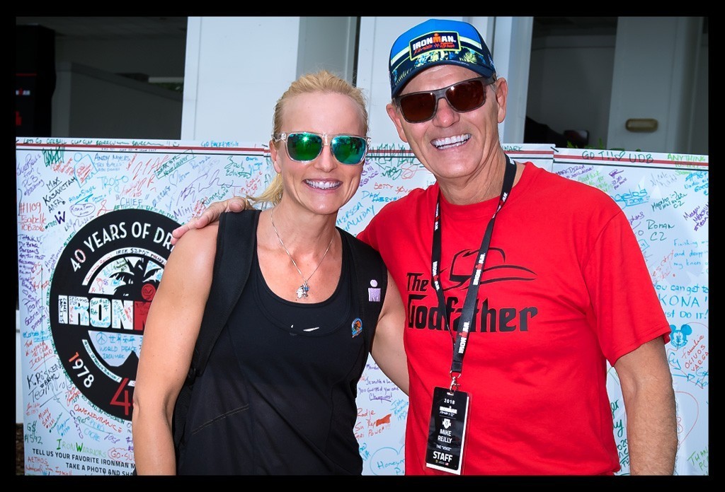 Mike Reilly the voice of Ironman und Nadin Triathletin und Autorin von eiswuerfelimschuh.de zusammen arm in arm mit Sonnenbrille lachen für ein Foto