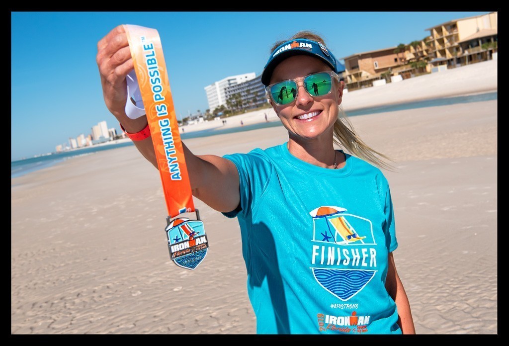frau triathletin nach wettkampf Ironman Florida Panama City Beach mit  medaillie strand sommer wasser ozean hotels freude lacht finisher t-shirt blau