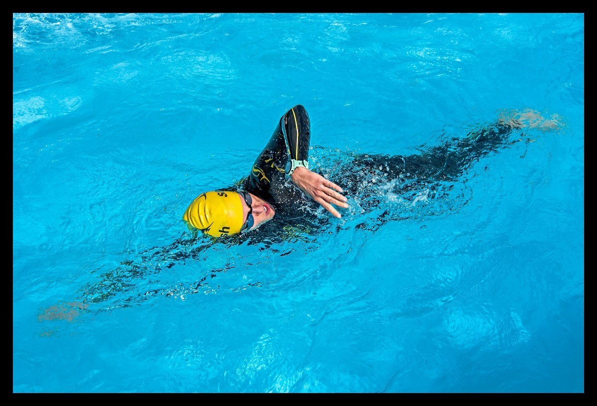 Triathletin schwimmt im blauem Wasser. Sie trägt einen Neoprenanzug von Sailfish, gelbe Badekappe, Schwimmbrille und Garmin Forerunner 745 Multisportuhr.  Produkttest. Review.