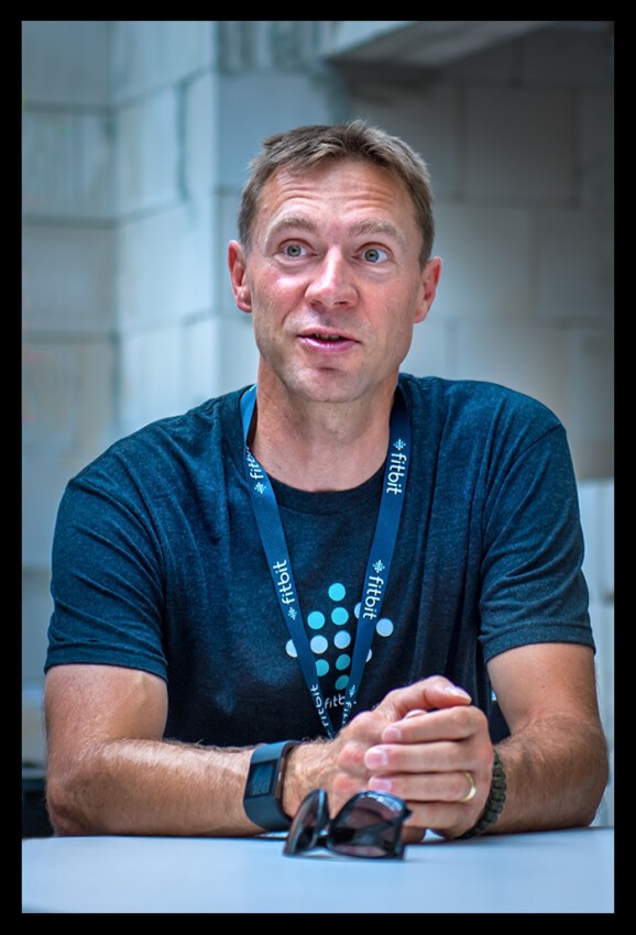 Jens Voigt Radsport Profi und Experte bei Presse Event mit Fitbit Uhr und blaues shirt spricht mit Teilnehmern