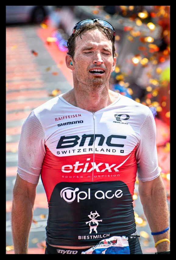 Ronnie Schildknecht Ironman Sieger Switzerland Legend Finish Line closing eyes confetti background celebration ear plugs BMC Sponsor Tri-Suit