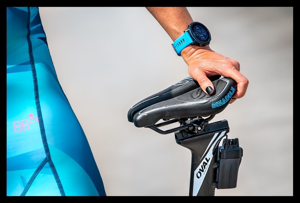 Triathletin im Tri-Suit Zeitfahrrad und BiSaddle Fahrradsattel für Triathleten und Radsportler Grossaufnahme von Hand auf dem Sattel.