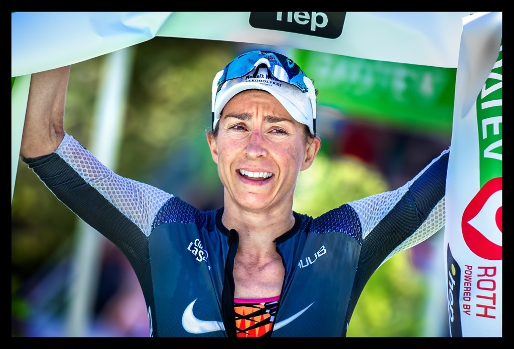 Anne Haug Weltmeisterin Ironman Siegerin Challenge Roth Ziel Schleife über Kopf Tri-suit blau cervelo hep lacht
