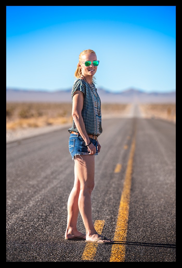 Reisebloggerinblonde Frau während Road Trip USA auf einsamer Landstraße in Nevada
