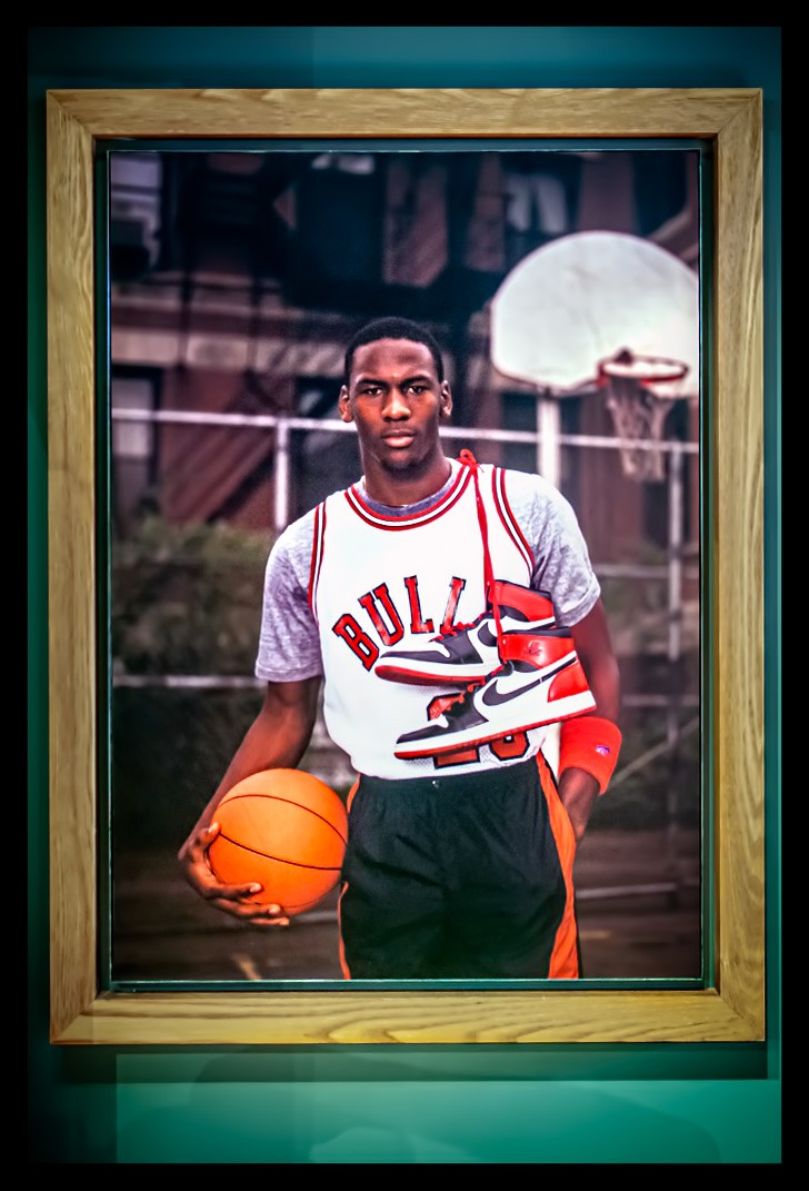 Michael Jordan in Bulls shirt und AIR Jordan Schuhe um Hals auf einem Baksketball Court posiert für Kamera auf einem Foto im NIKE Store