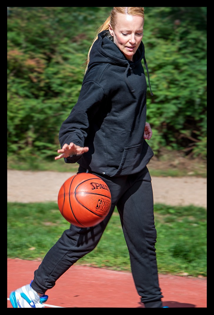 Frau mit Garmin Smartwatch spielt Basketball und AIR Jordan Schuhe streetball court sommerlich dribbelt nba ball spalding