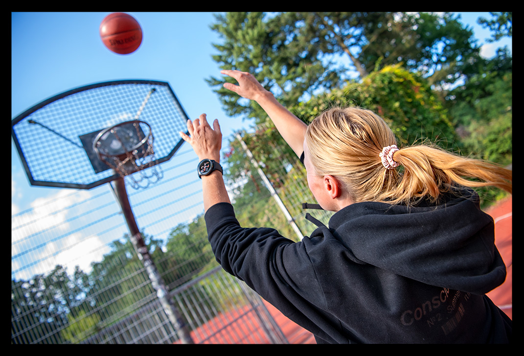Frau mit Garmin Smartwatch spielt Basketball und AIR Jordan Schuhe streetball court sommerlich Test von neuer Venue 2