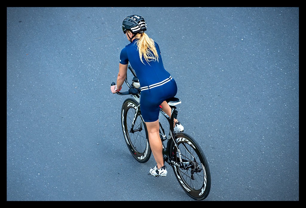 frau triathlon skin suit tri-bike blauer tri-suit blonde haare pferdeschwanz dynamisch wiegetritt aero straße obern aufgenommen zipp räder