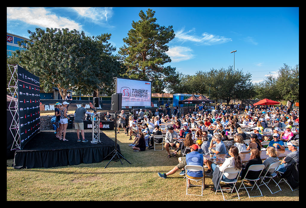 Siegerehrung award ceremony Ironman Arizona Tempe USA. Viele Zuschauer sitzen auf stühlen auf Rasen.Sommerliche stimmung