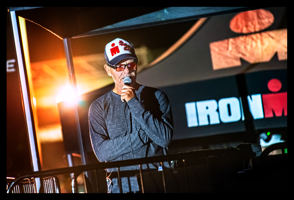 Ironman-Arizona-Tempe finishline with Mike Reilly on stage fireworks and flashlights red carpet "M" Logo Ironman. Mike with microfon commentating with Basecaop #200