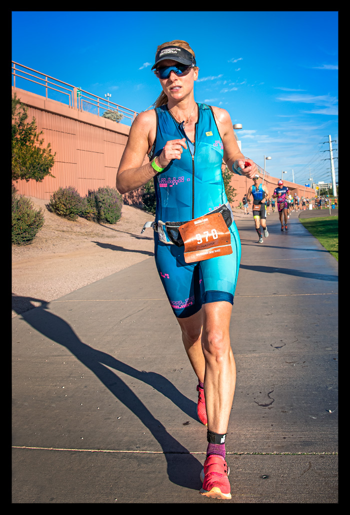 Triathletin Nadin Ironman Arizona USA bei sonnenschein Laufstrecke ganzkörper aufnahme Laufstrecke. Blauer Tri-Suit rote Schuhe Garmin Forerunner