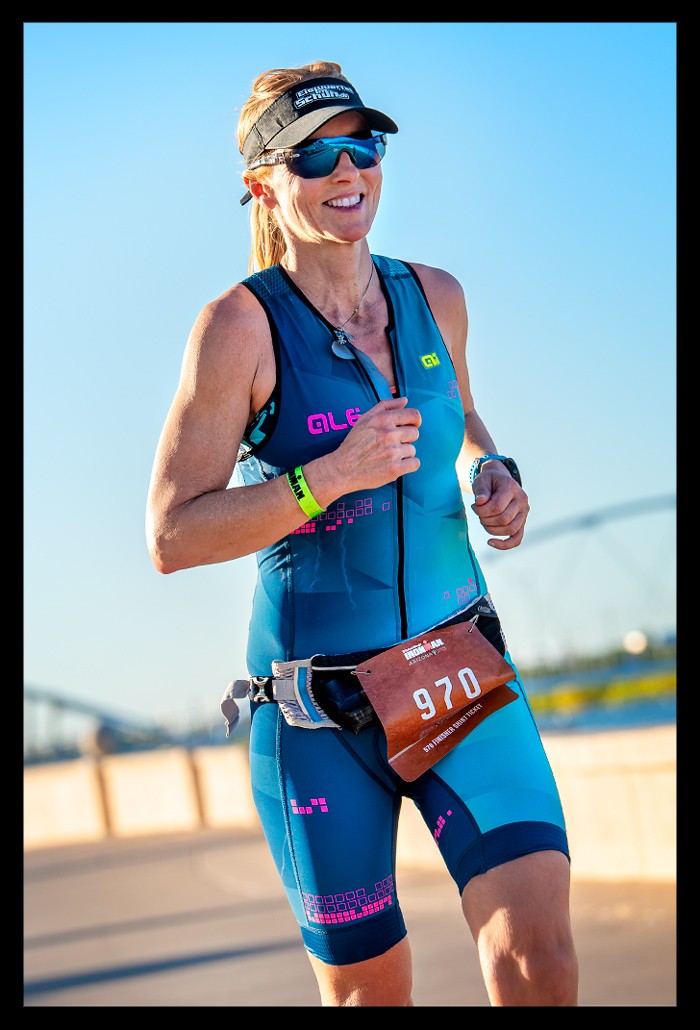 Nadin, Bloggerin und Triathletin von eiswuerfelimschuh.de beim Ironman in Tempe Arizona USA auf der Laufstrecke. Blaue Tri-Suit von ALE und sonnenbrille auf dem Kopf. Garmin Forerunner am Handgelenck. Brücke im Hintergrund