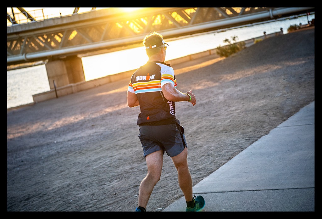 Ironman in Tempe Arizona USA Athlet mit Ironman Trikot auf der Laufstrecke sonnenunergang warmes licht