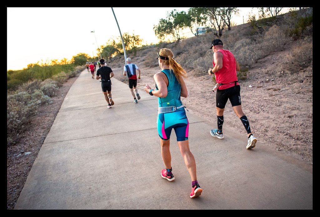 Ironman in Tempe Arizona USA Athletin von hinten auf der Laufstrecke mit sonnenuntergang