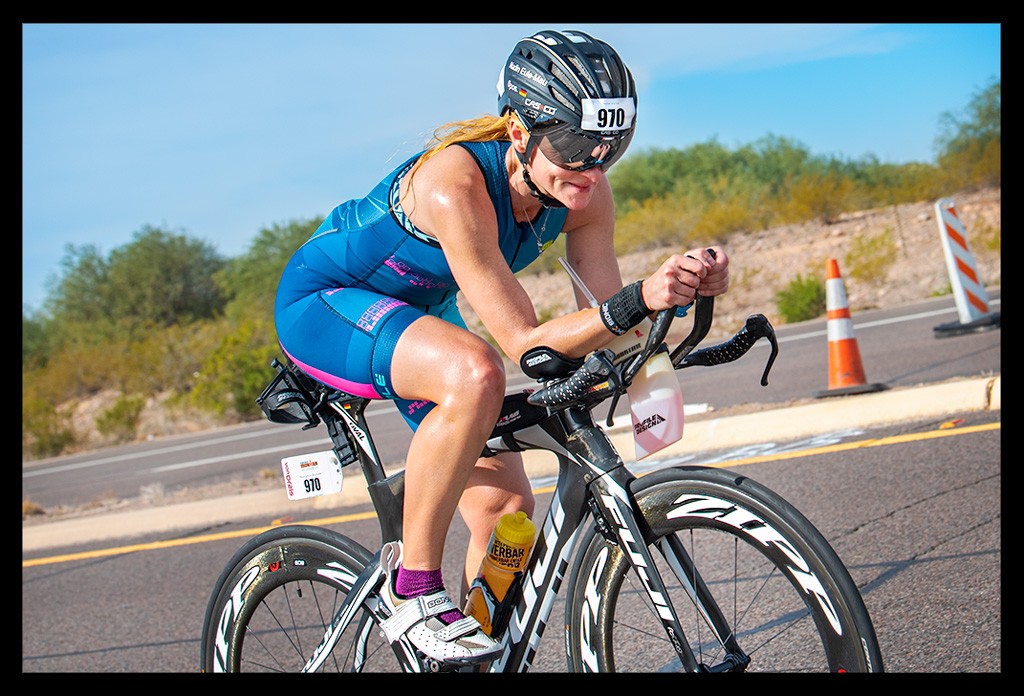 Triathletin und Bloggerin auf der Radstrecke beim Ironman Arizona in TriSuit auf Zeitfahrrad lachend