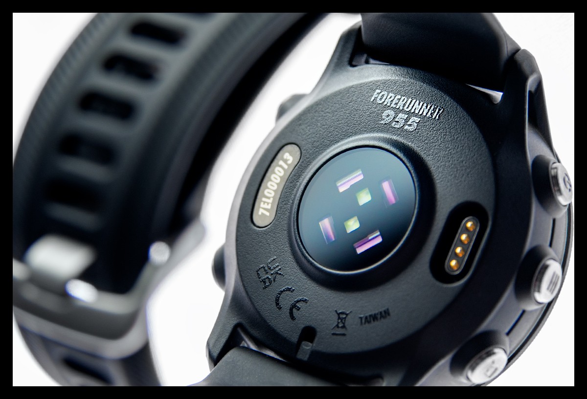 Garmin Forerunner 955 Multisportuhr GPS detaillierte Nahaufnahme vom PulseOx und HF Sensor sowie Metall Tasten Button und Anschluss Ladekabel. Schriftzug Forerunner 955 auf Gehäuse zu sehen mit Armband in schwarz