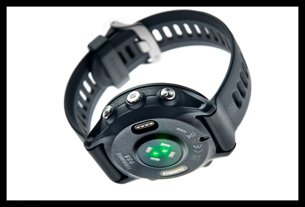 Garmin Forerunner 955 Multisportuhr GPS detaillierte Nahaufnahme Unterseite mit vom PulseOx und HF Sensor sowie Metall Tasten Button und Anschluss für Ladekabel. Schriftzug Forerunner 955 auf Gehäuse zu sehen mit Armband in schwarz. Sensoren leuchten Grün. Uhr scheint in der Luft zu schweben