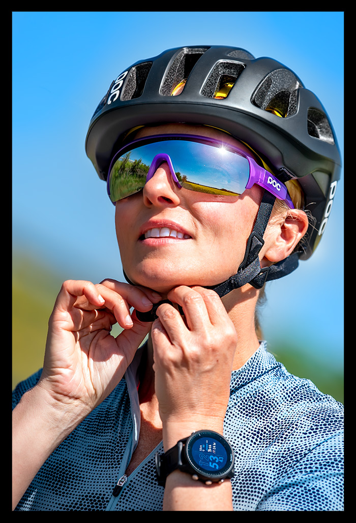 Frau Radsport Triathlon posiert hände schliessen helm MIPS system poc sports octal schwarz garmin multisportuhr 955 reflexion sonne in brille