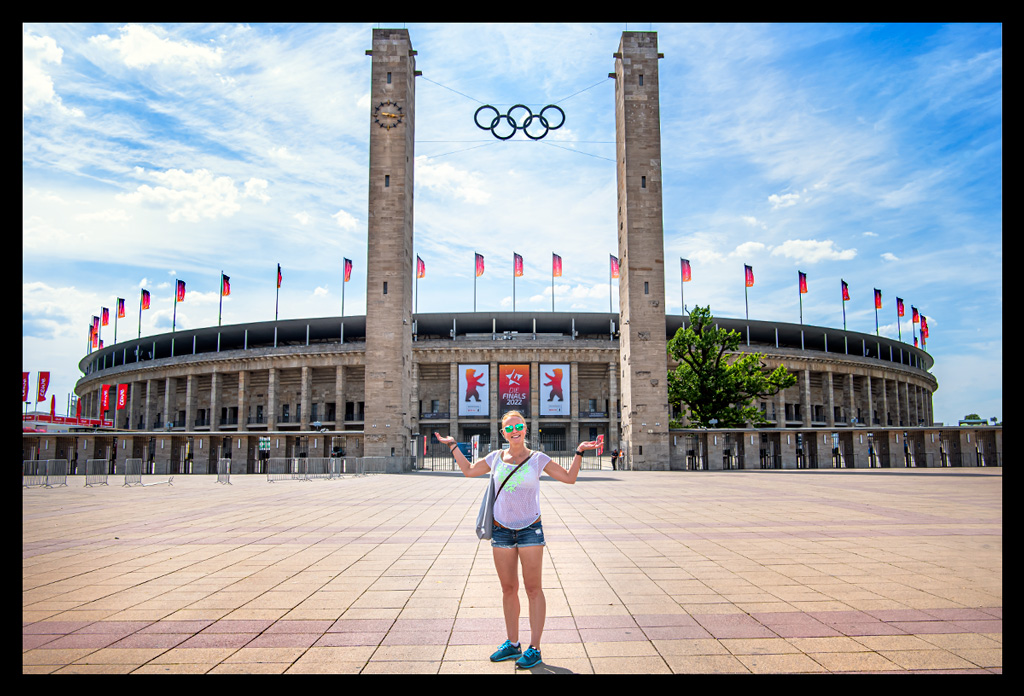 olympiastadion berlin haupteingang olympische ringe finals sommerlich frau davor weiße bluse handgeste schaut mal her triathlon startunterlagen sprintdistanz