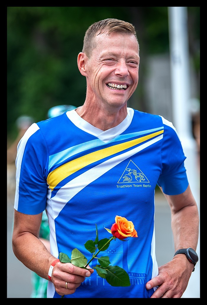 triathlet siegerehrung mit blumen rosen altersklassen athleten city triathlon berlin sprintdistanz dtu olympischer platz die finals 2022 lächelt freude tem berlin blaues shirt