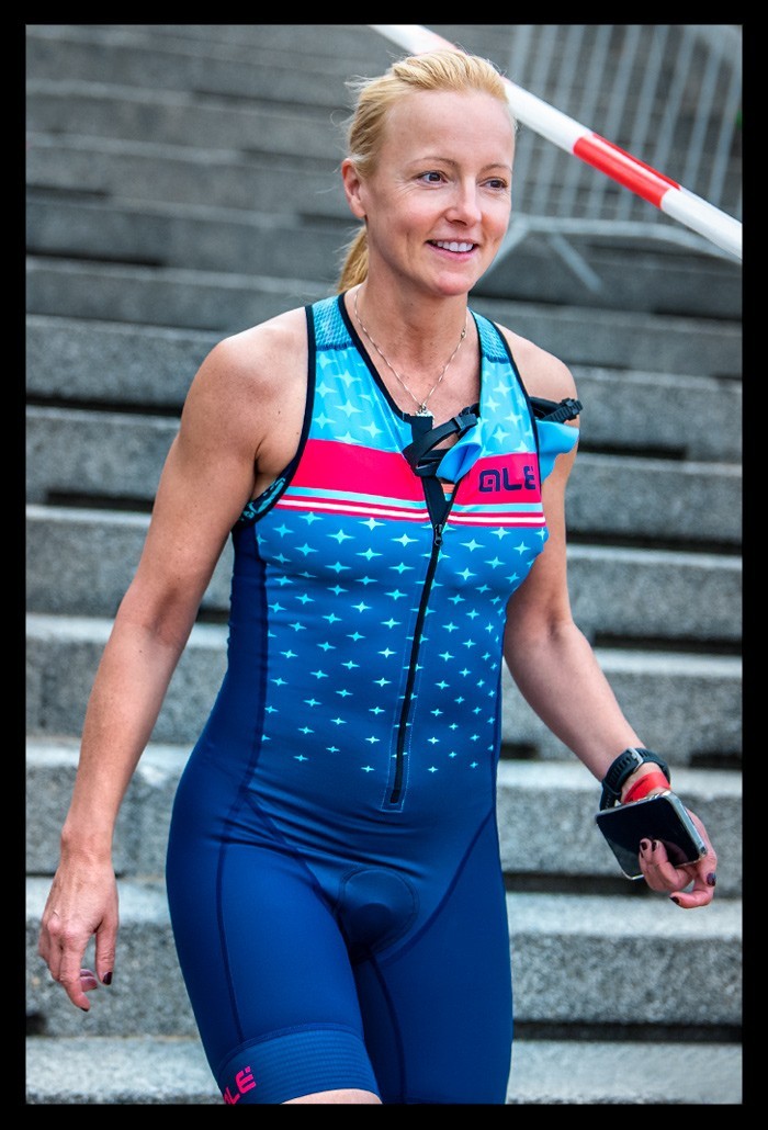triathletin blonde haare blauer tri-suit rennanzug lächelt vor schwimmstart läuft treppen strandbad wannsee berlin die finals 2022 city triathlon sprintdistanz