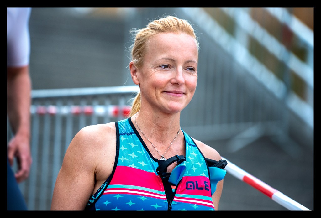 triathletin blonde haare blauer tri-suit rennanzug lächelt vor schwimmstart läuft treppen strandbad wannsee berlin die finals 2022 city triathlon sprintdistanz