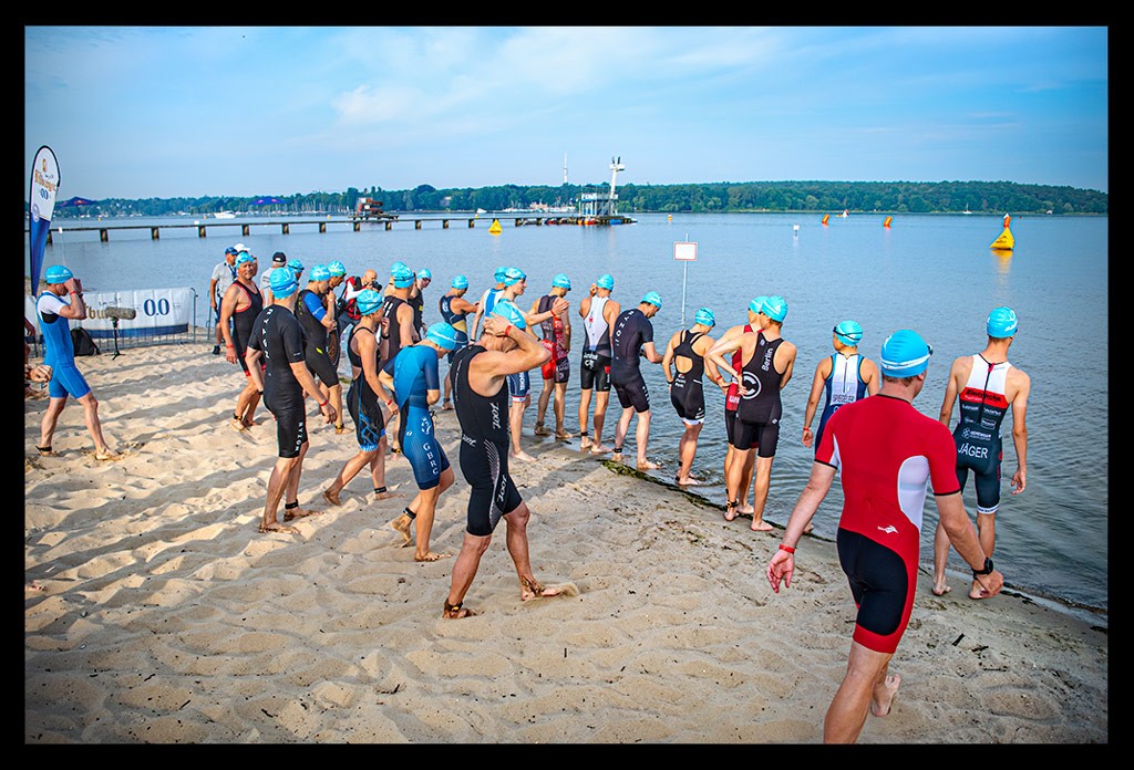triathleten gehen an start schwimmen strandbad wannsee dtu triathlon sprintdistanz finals berlin 2022 sommerlich wasser landschaft rettungsturm dlrg