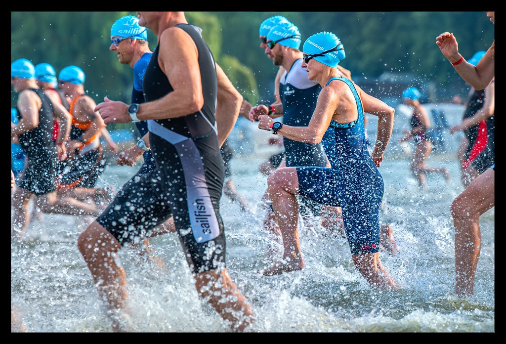 triathletin nadin wasserstart beim sprintdistanz triathlon finals berlin wannsee blauer tri-suit ale cycling badekappe andere athleten daneben wasserspritzer