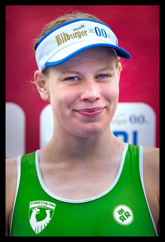 Laura Lindemann portrait lächelt siegerin deutsche meisterschaft triathlon sprintdistanz Potsdam e.V. finals berlin grüner rennanzug bitburger cap siegerehrung