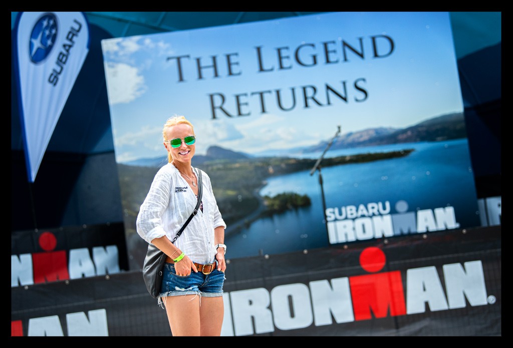 Triathletin Ironman und Sportbloggerin Nadin lächelnd vor einem Ironman Canada Kanada Penticton Banner mit dem Schriftzug The Legend Returns