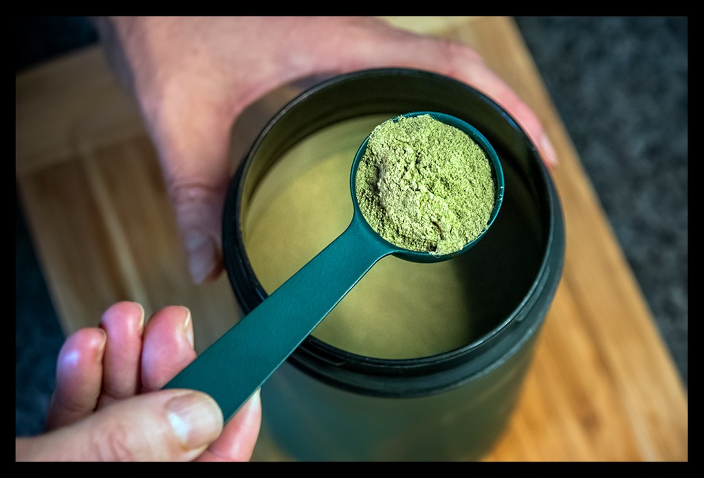 Athletic Greens AG1 Produkt Nahrungsergänzungsmittel grünes Pulver mit Löffel in küche
