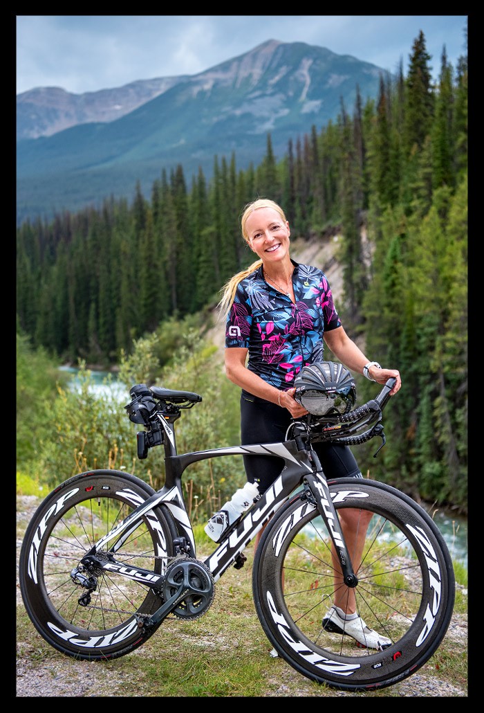 triathletin mit zeitfahrrad posiert in den bergen von kanada mit landschaft im hintergrund und testet Garmin EDGE 1040 solar