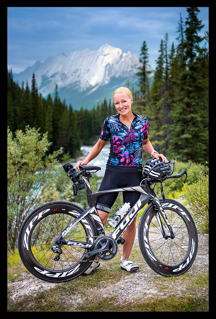 triathletin mit zeitfahrrad posiert in den bergen von kanada mit landschaft im hintergrund und testet Garmin EDGE 1040 solar
