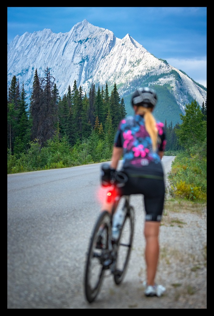 Radsportlerin mit Garmin VARIA Bike Radar RCT716 Rücklicht mit Kamera steht strasse in kanada endlose weite Berge Landschaft autoverkehr sicherheit testet gerät für beitrag