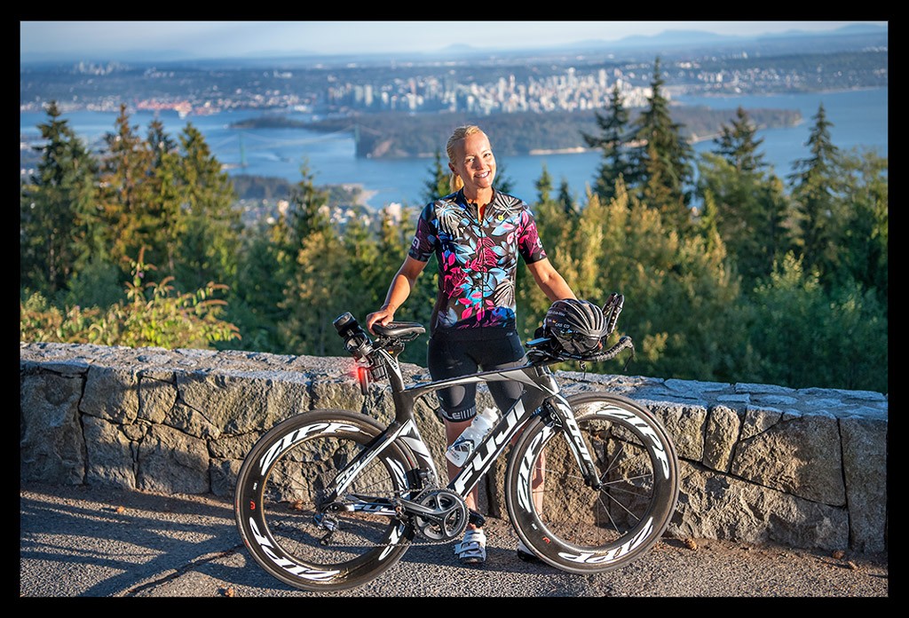 Nadin Eule Triathletin testet Garmin VARIA Bike Radar RCT716 und Rücklicht mit Kamera in Kanada steht mit blick auf Vancouver und zeitfahrrad buntes radtrikot und lächelnt vor aussicht
