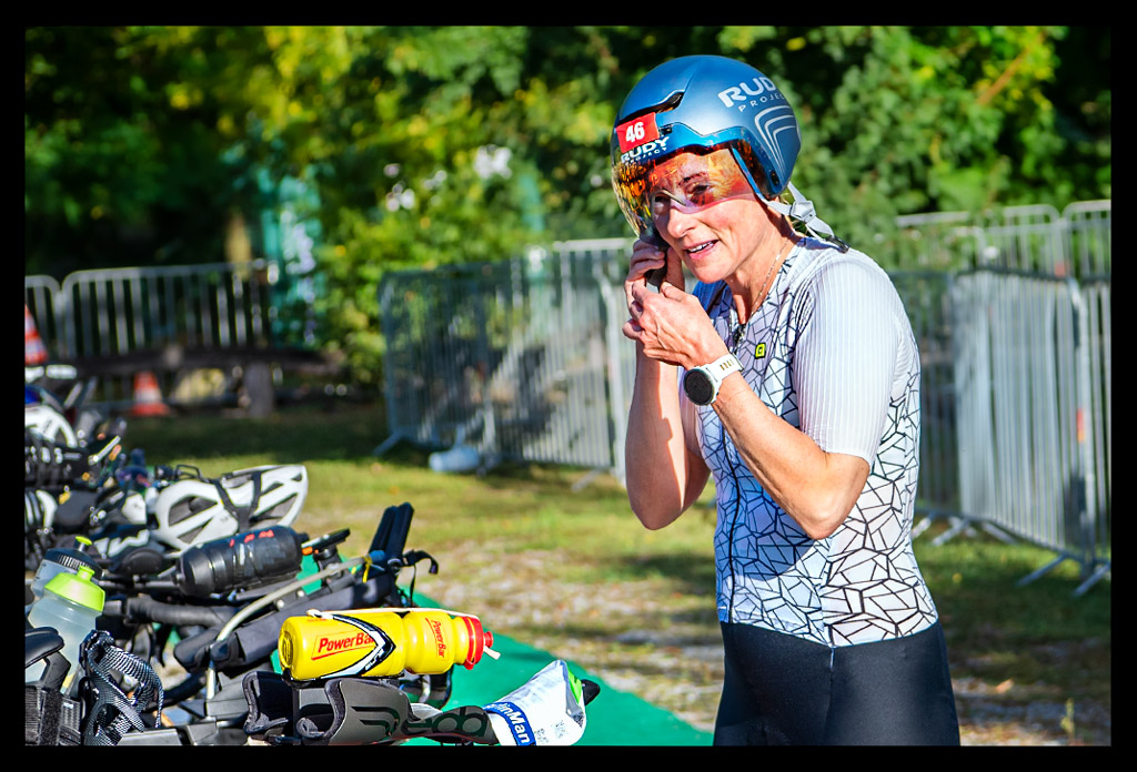 Triathletin mit Zeitfahrhelm im Wechselbereich des BerlinWoMan-Triathlons am Zeitfahrrad stehend